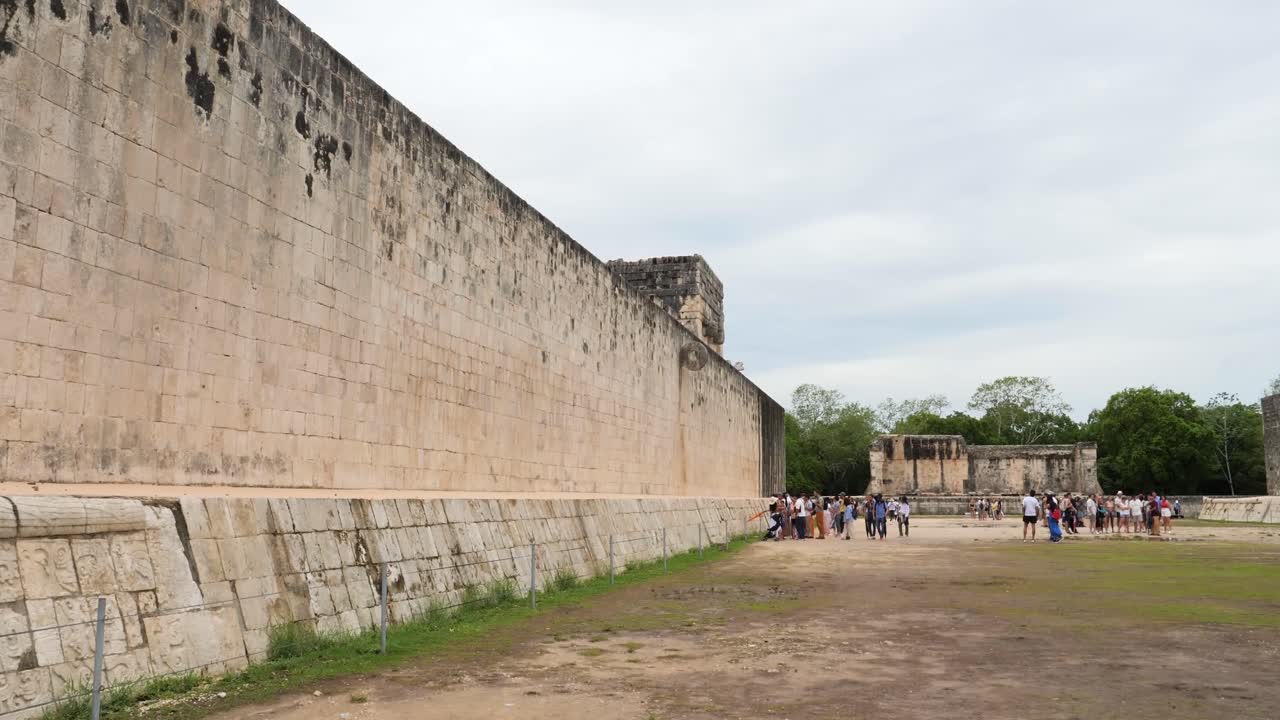 Tourists visiting The Great Ball Court in Chichen Itza. The east wall, Stone Ring located 9 m (30 ft) above the floor and the South Temple.