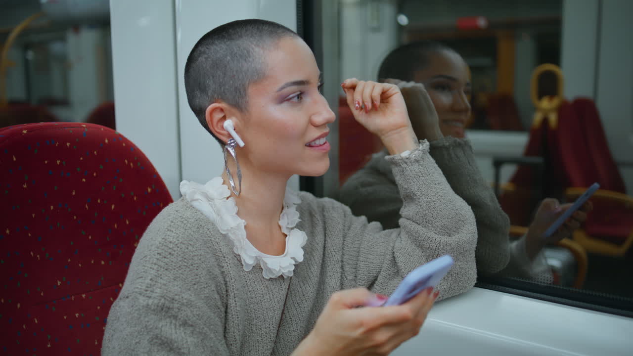 Woman using smartphone and earbuds on a train