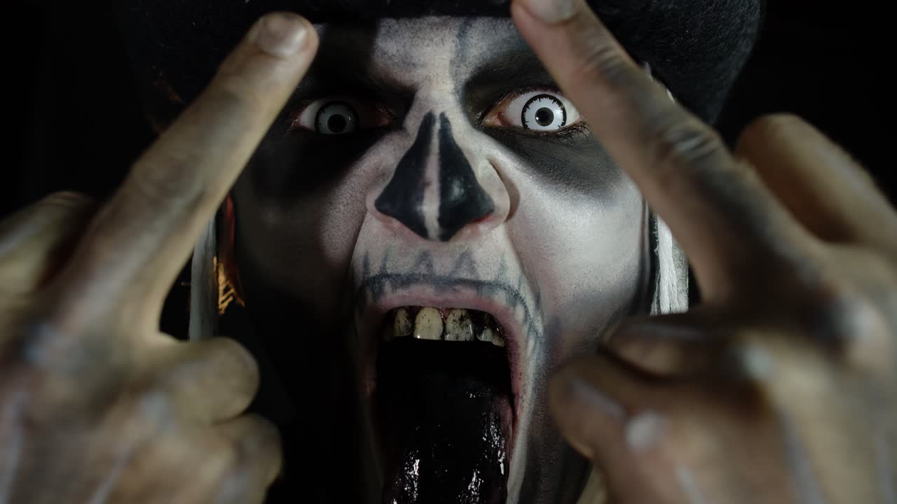 hombre siniestro con maquillaje de cráneo haciendo caras y mostrando el dedo medio. mal comportamiento gesto. halloween