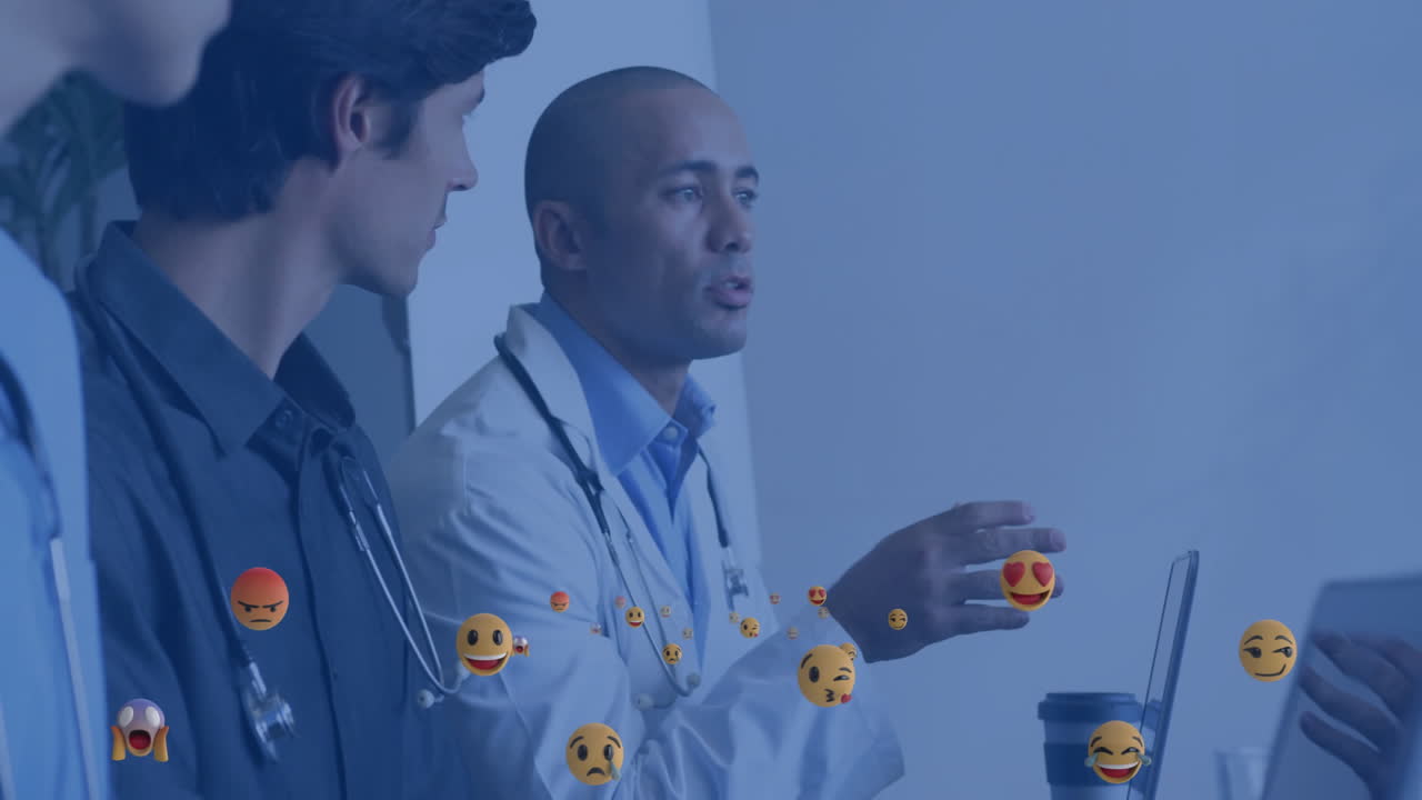 Doctors discussing clinical data on laptop, showcasing floating emoji icons in health industry