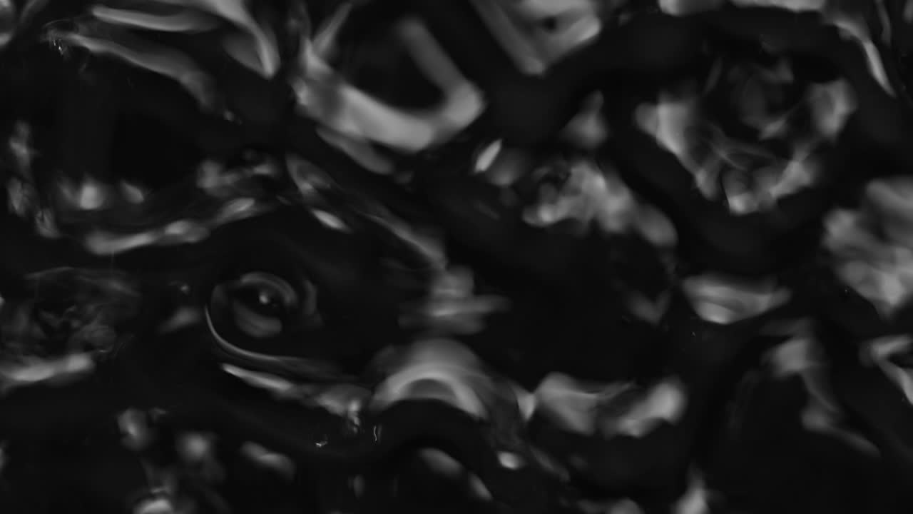 salpicaduras y gotas en la superficie del líquido. abstracto fondo negro vibración del agua. 4k cámara lenta 100 fps, prores 422, 10 bits