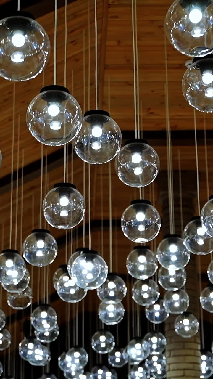 Many round light bulbs background. Beautiful ceiling with shining glass balls hanging on long white wires. Glamour ceiling. Vertical video