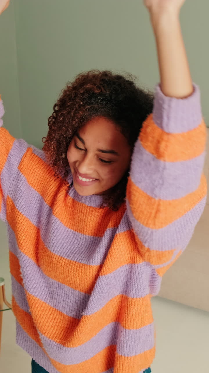 Joyful Young Woman with Curly Hair Smiling and Dancing
