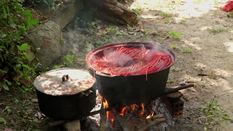 dyed straw strands cooking in large pot on the fire