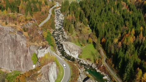 aerial view of cars driving on mountain pass in val di mello during autumn in lombardy, italy