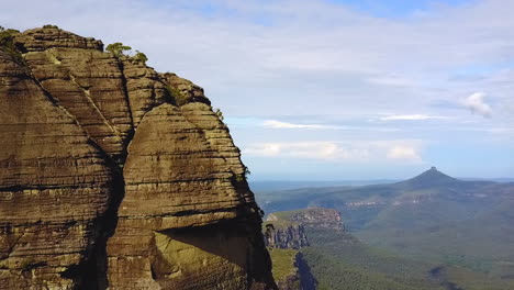 drone circling cliff face revealing mountains and rocky escarpments in the background