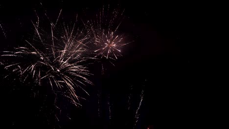 exploding fireworks illuminate the night sky with bright, radiating streaks