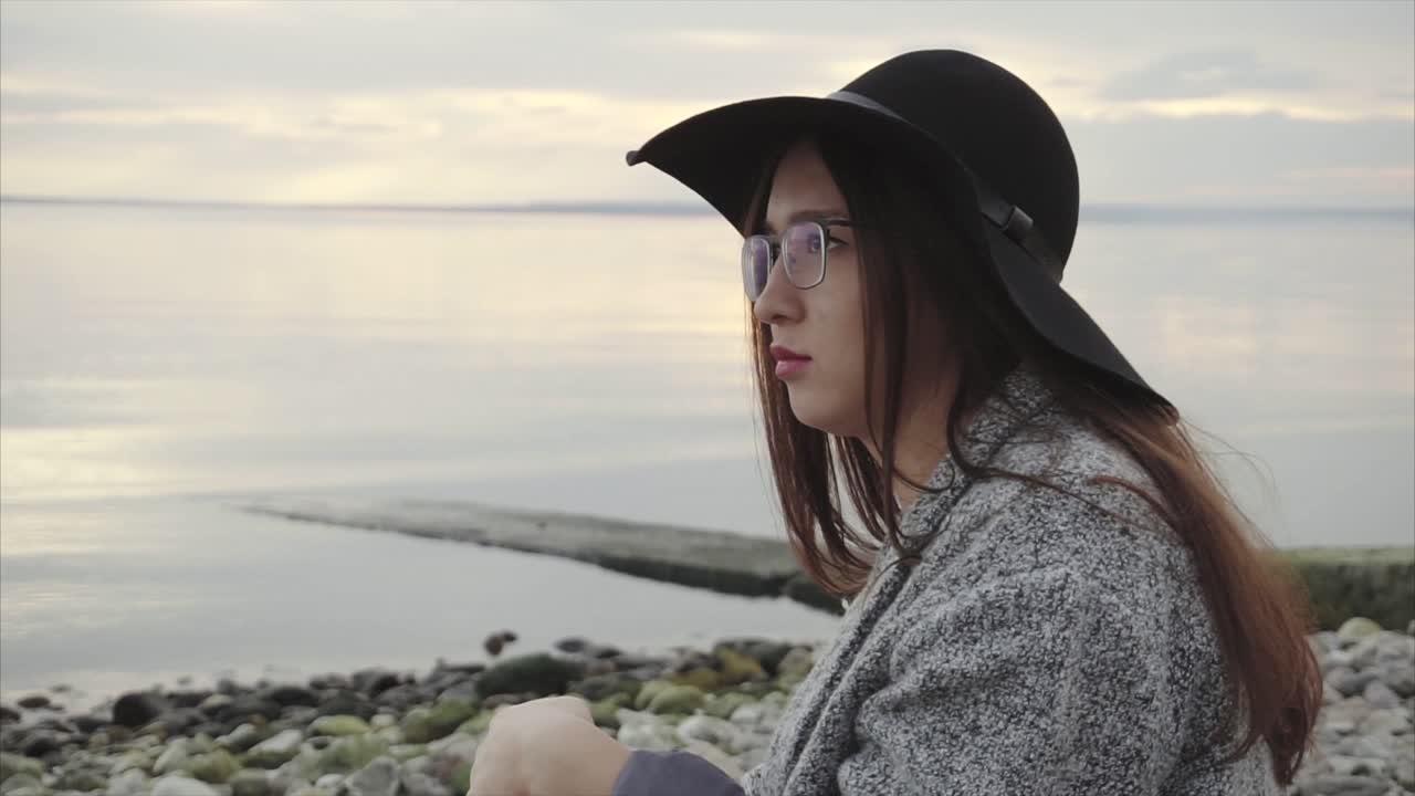mujer sentada en la playa al atardecer