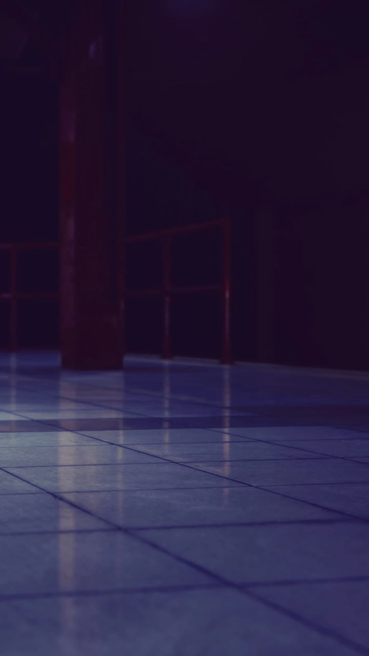 Dark indoor space with tiled floor and a visible column in the center