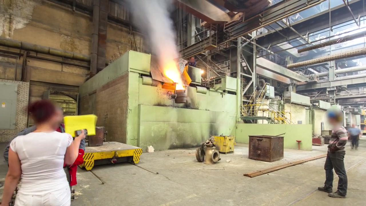 Il metallo liquido viene versato negli stampi in un impianto metallurgico in timelapse hyperlapse. Officina di fabbrica con forno per la produzione dell'acciaio. Operaio che controlla la gru per la fusione del metallo nei forni