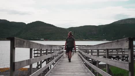 backpacker with alaskan malamute dog walking on wooden platform jetty