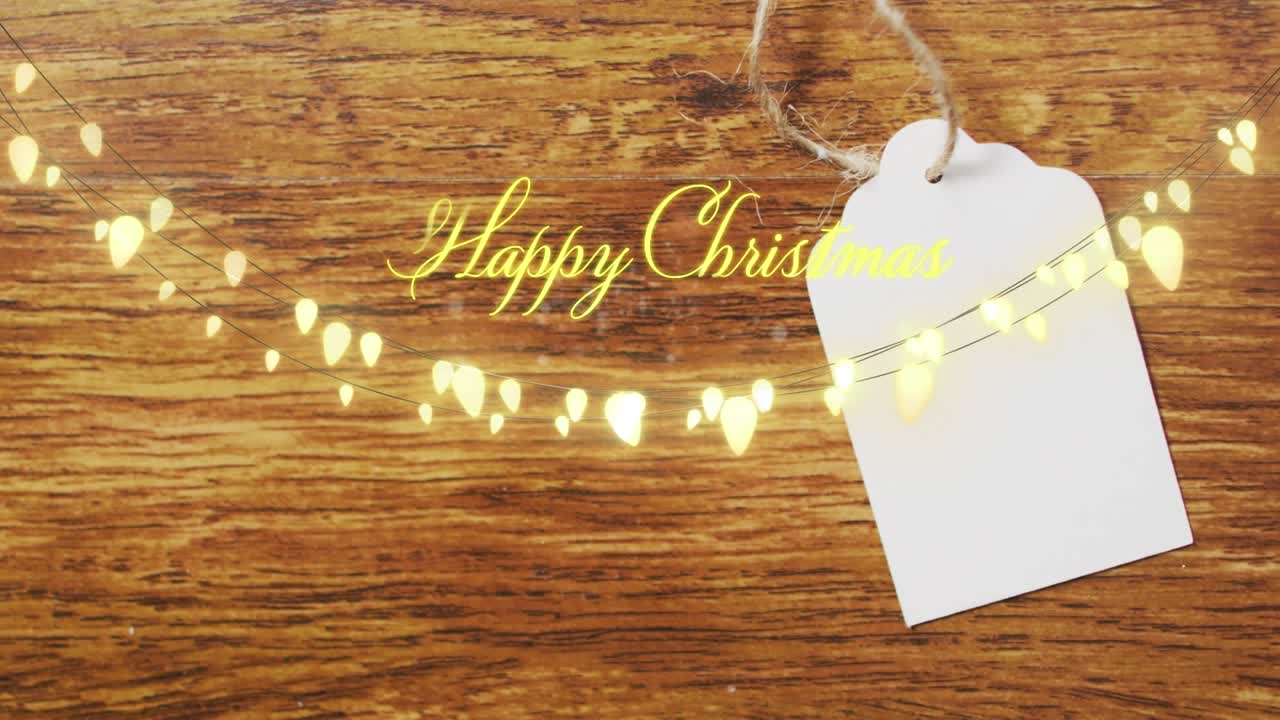 Animation of happy christmas text with fairy lights over gift tag
