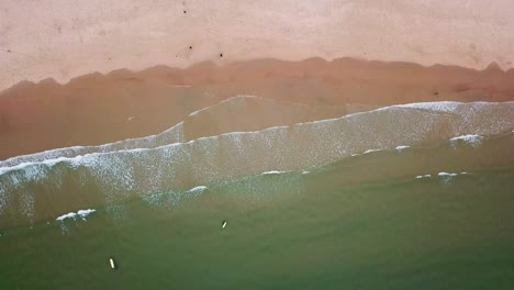 a tranquil aerial perspective of baleal, portugal, featuring serene sandy beaches, gentle waves meeting the shore, and surfers enjoying the ocean’s embrace