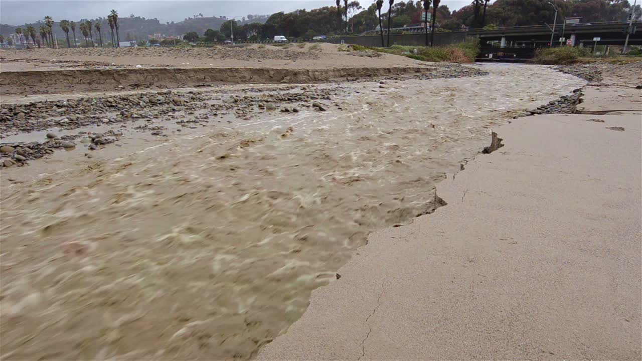 벤추라 캘리포니아에서 폭우가 내린 후 산존 개울이 해변 모래를 바다로 씻는 패닝 샷