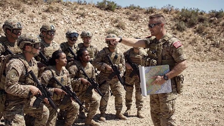 Esercitazione di addestramento militare: soldati impegnati in esercitazioni tattiche e coordinamento in terreno arido con mappe e equipaggiamento da combattimento.