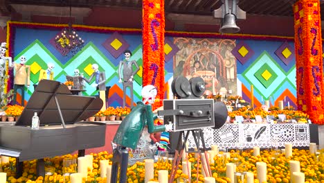 day of the dead offering in front of government building in coyoacan city hall in mexico city consisting of several cempasúchil flowers, candles and skulls dressed as famous mexican characters