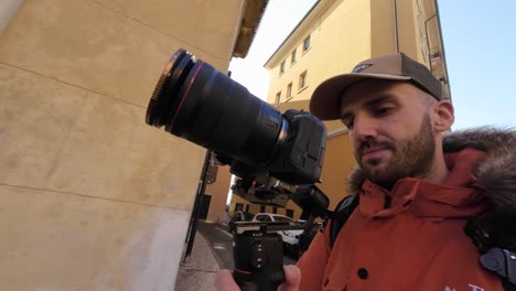 man walking along city street of verona while holding professional camera mounted on stabilizing gimbal dji rs3 mini