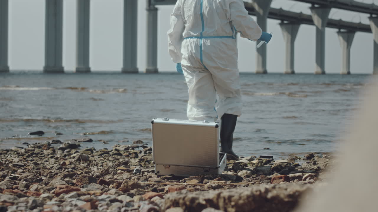 Ecologist in Coveralls Collecting Water Sample in Polluted Gulf