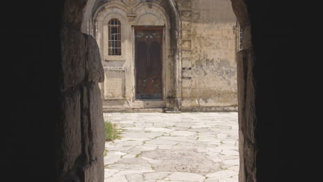 pov from the inside of mysterious dark passage leading out to a medieval square