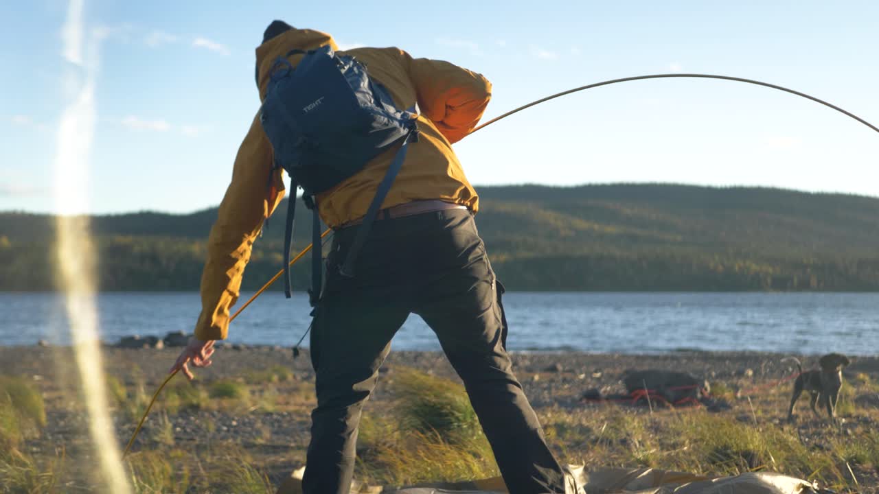 Setting up first supporting arch pole to raise camping tent, in Sweden - Medium slow motion shot