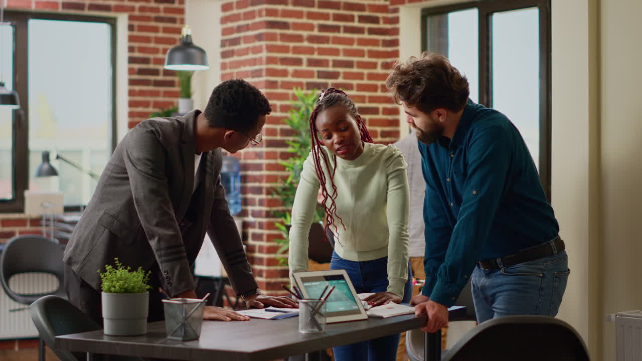Multiethnic group of coworkers analyzing information on charts