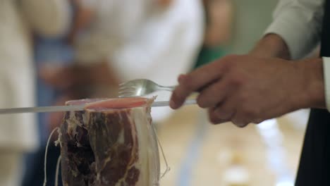 male slicing delicious slice of dried prosciutto on table, slowmotion closeup