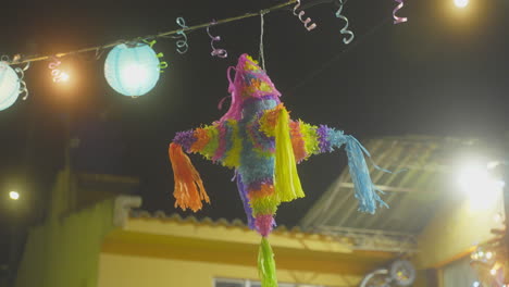 multicoloured tissue paper party decoration hanging in a courtyard at night time
