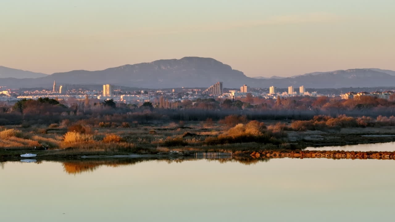 몽펠리에의 파노라마 뷰와 조용한 전면 물, 그 너머의 산.