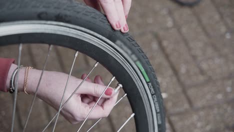 la señora ajusta la presión de aire en los neumáticos de su bicicleta eléctrica e instala la tapa de la válvula en el neumático de la bicicleta afuera