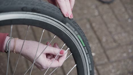 lady adjusts the air pressure in her electric bike tires and installs the valve cap on the bike tire outside