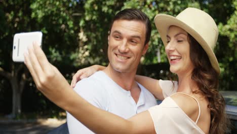 couple taking a selfie on mobile phone near car