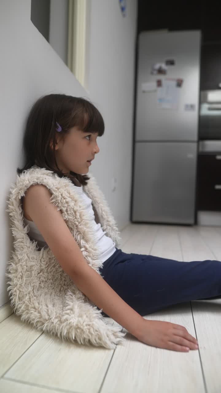 Una chica triste sentada en el suelo.