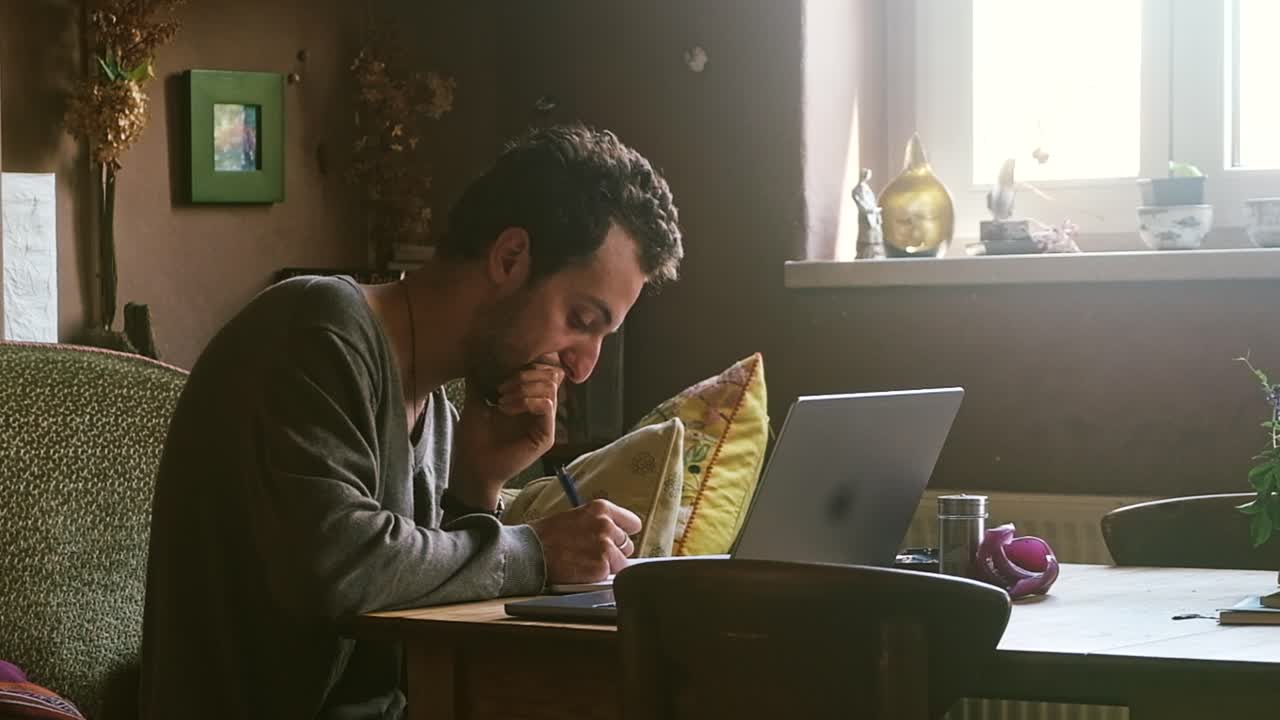 Man working on laptop at desk in cozy indoor setting, focused and engaged