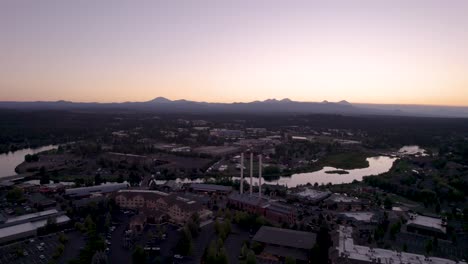 Bend-Oregon-Sonnenuntergang-–-Von-Links-Nach-Rechts-Schwenkende-Drohnenaufnahme-Der-Alten-Mühle,-Des-Deschutes-River-Und-Der-Kaskadenberge