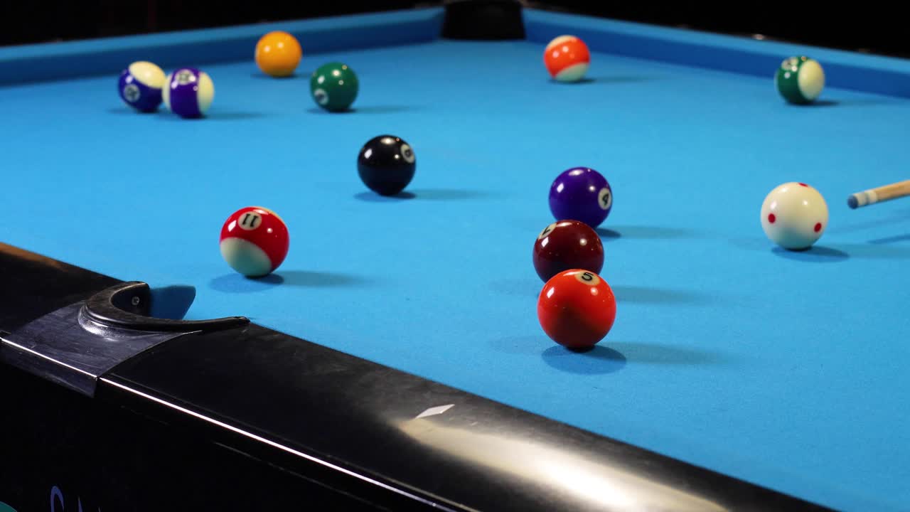 Playing a game of billiards pool hitting cue ball with cue stick
