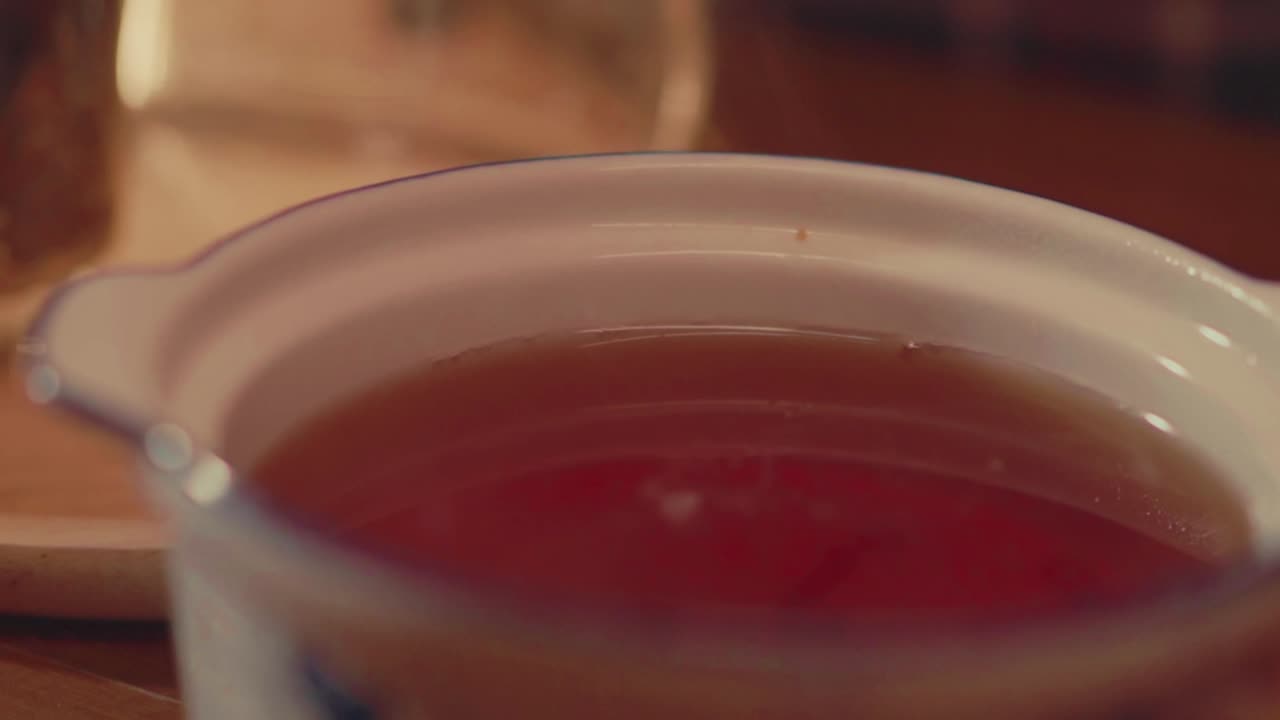 Close-up of tea being gently stirred in a ceramic bowl. Perfect for themes of wellness, calm living, natural drinks, and handcrafted tea preparation.