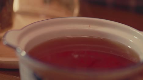 close-up of tea being gently stirred in a ceramic bowl. perfect for themes of wellness, calm living, natural drinks, and handcrafted tea preparation.