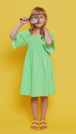 child kid girl holding magnifying glass looking into camera with big zoomed funny eye analysing