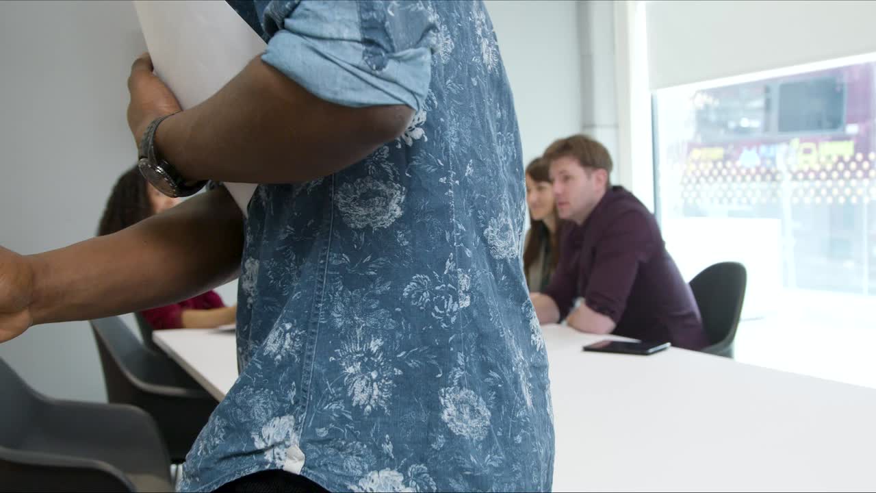 un hombre entra en una reunión de negocios con sus colegas.