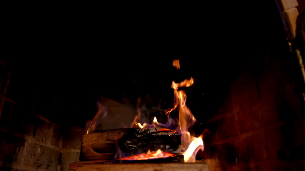 Fire is burning in the fireplace. Pleasant hearth at home. Warmth and home comfort. Fire flame on wooden logs in brick fireplace in a country house.