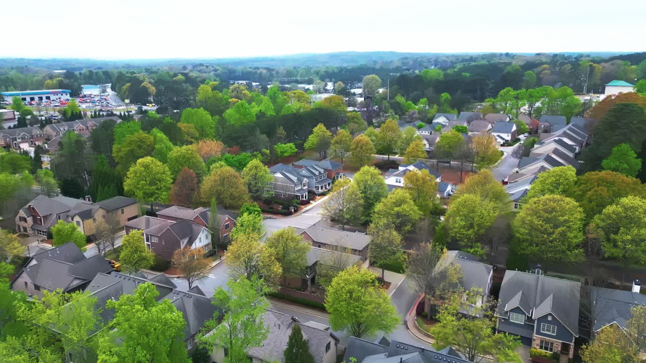 New Developed housing area with green trees and luxury houses in suburb of Atlanta, Georgia. Aerial approaching flight. Modern Single family houses with grey roofs. Wide shot.