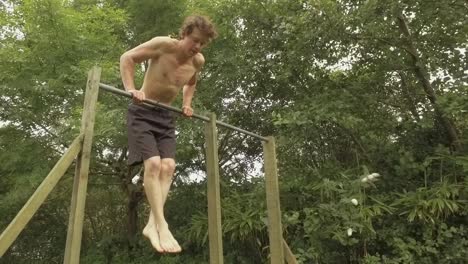 young athletic man performs straight bar dips on outdoor gym