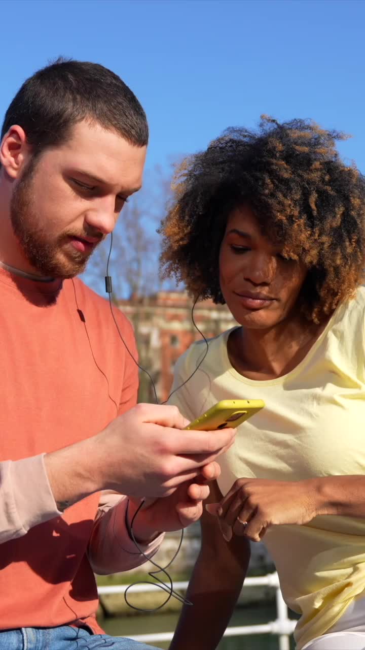 Couple sharing earphones listening to music in the city