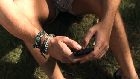 hombre sentado en la hierba y usando teléfono móvil
