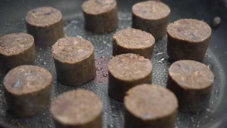 frying slices of sausage on non-stick pan at restaurant