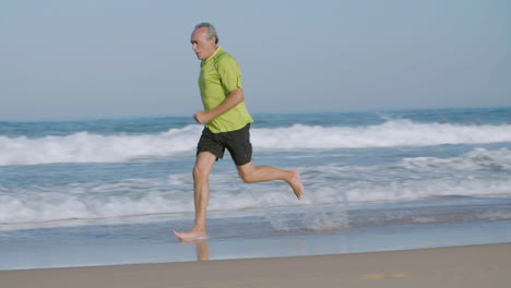 Hombre-Confiado-Corriendo-Descalzo-Rápido-En-La-Playa-De-Arena