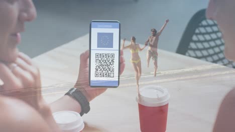 animation of woman holding smartphone with covid 19 vaccination passport over people on the beach