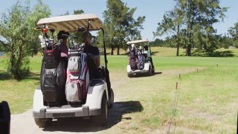 senior people driving a golf cart with clubs on the back at golf course