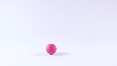 una pelota rosa rebota en una superficie blanca