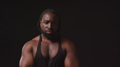 retrato de un atleta masculino serio con chaleco de fitness con entrenamiento físico muscular preparándose para un evento deportivo contra un fondo de estudio negro